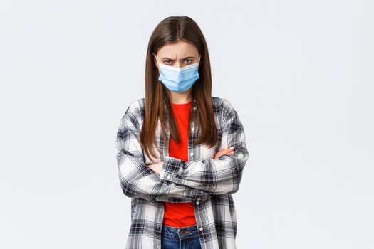 Coronavirus outbreak, leisure on quarantine, social distancing and emotions concept. Angry young mad girlfriend in medical mask and checked casual shirt, feel offended, sulking and stand defensive.