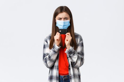 Coronavirus outbreak, working from home, online shopping and contactless payment concept. Angry or frustrated young woman in medical mask frowning displeased, holding credit card.