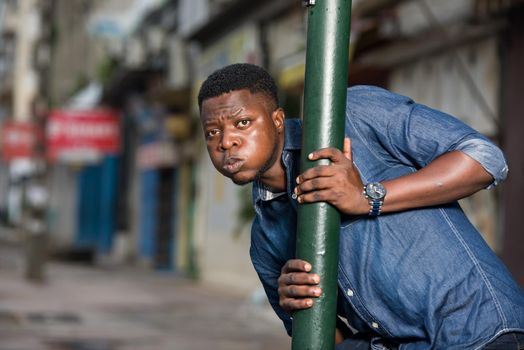 young african man behind iron bar looking at the camera, surprised.