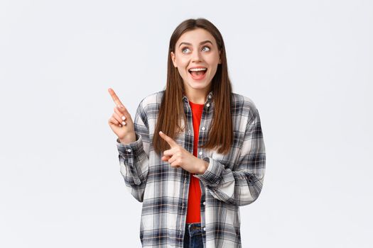 Lifestyle, different emotions, leisure activities concept. Excited happy woman in checked shirt pointing fingers upper left corner and smiling amused, making choice, found what she look for.