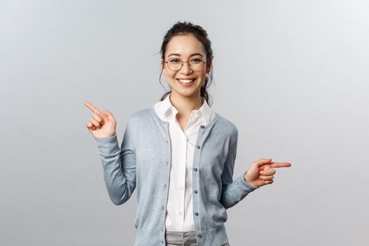 Advertisement, education and people concept. Girl recommends both products. Cheerful young asian woman in glasses pointing sideways, showing left and right promo with pleased smile.