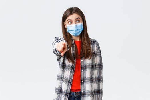 Coronavirus outbreak, leisure on quarantine, social distancing and emotions concept. Astonished and impressed, excited girl recognize someone, pointing finger camera, wear medical mask.