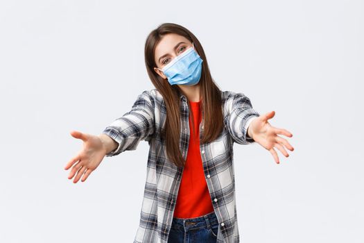 Coronavirus outbreak, leisure on quarantine, social distancing and emotions concept. Friendly-looking young supportive girl in medical mask reaching hands to give hug or hold something.