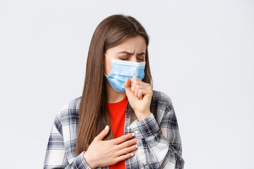 Coronavirus outbreak, leisure on quarantine, social distancing and emotions concept. Close-up of sick young woman in medical mask staying at home during covid-19, cough with closed eyes.