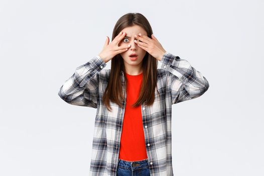 Lifestyle, different emotions, leisure activities concept. Shocked and speechless young pretty female in checked shirt, cover eyes from cringy thing but peeking through fingers.