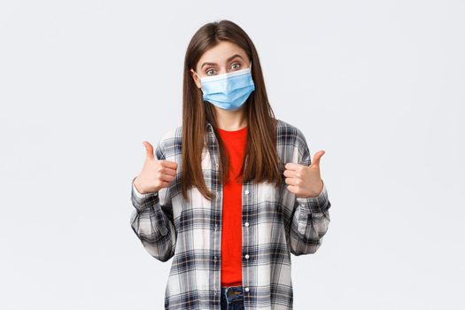 Coronavirus outbreak, leisure on quarantine, social distancing and emotions concept. Very good congratulations. Supportive cute woman in medical mask show thumb-up, like and approve.