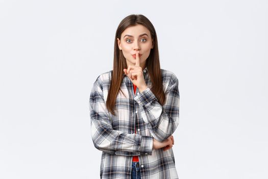 Lifestyle, different emotions, leisure activities concept. Silly cute girl in checked casual shirt asking keep secret, kindly shush with index finger over lips, want person keep voice down, be quiet.