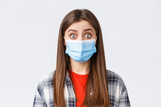 Coronavirus outbreak, leisure on quarantine, social distancing and emotions concept. Close-up of intrigued, surprised woman hear interesting news, wear medical mask, widen eyes.