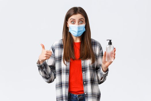 Coronavirus outbreak, leisure on quarantine, social distancing and emotions concept. Amazed and impressed girl in medical mask, want prevent catching virus, thumb-up good hand sanitizer.