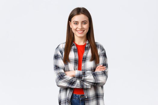 Lifestyle, different emotions, leisure activities concept. Cheerful young caucasian girl, female student in checked casual shirt, cross arms chest and demiling pleased, standing white background.