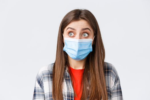 Coronavirus outbreak, leisure on quarantine, social distancing and emotions concept. Close-up of surprised caucasian woman in casual clothes and medical mask, staring left speechless.