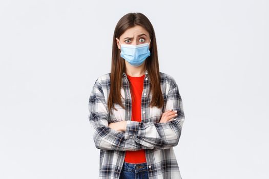 Coronavirus outbreak, leisure on quarantine, social distancing and emotions concept. Shocked and confused young pretty teenage girl hear strange news, raise eyebrows puzzled, wear medical mask.