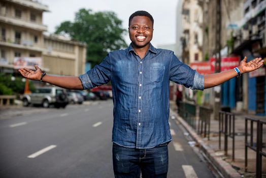 young happy man making welcome gesture in the street.He is happy to meet his dear guests and show his city