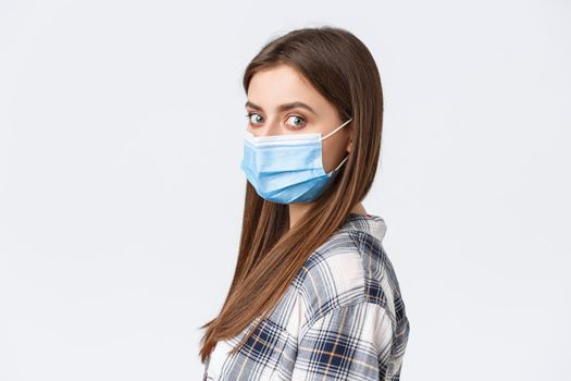 Coronavirus outbreak, leisure on quarantine, social distancing and emotions concept. Profile shot of serious young attractive woman, student in medical mask turn face camera.