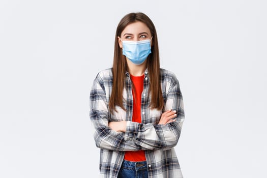 Coronavirus outbreak, leisure on quarantine, social distancing and emotions concept. Happy and dreamy young optimistic woman, beautiful girl in medical mask laughing and looking upper left corner.