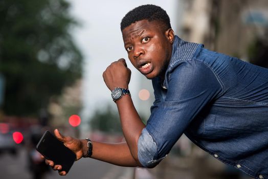 young man in jeans with his elbows on iron bar staring at the camera with surprise.
