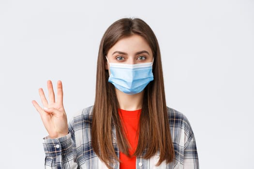 Coronavirus outbreak, leisure on quarantine, social distancing and emotions concept. Cheerful attractive woman in medical mask showing number four, make order, white background.