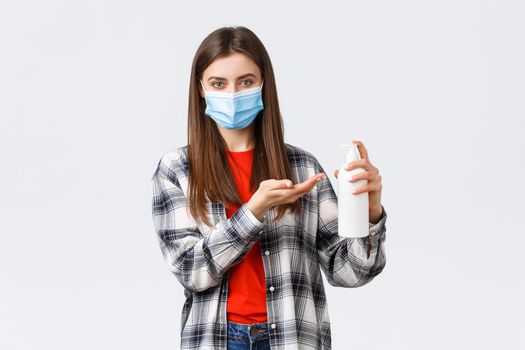 Coronavirus outbreak, leisure on quarantine, social distancing and emotions concept. Young woman taking care of health, preventing virus measures, apply soap or hand sanitizer, wear medical mask.