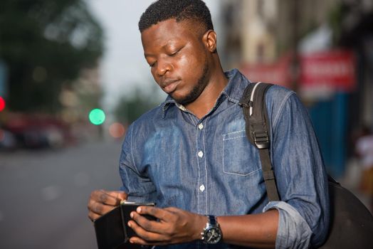 young man standing in jeans backpack looking at address book.