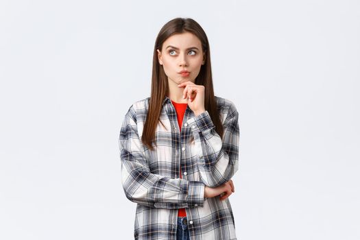 Lifestyle, different emotions, leisure activities concept. Smart woman in checked casual shirt searching solution, thinking and looking up, touch chin as pondering decision, making choice.