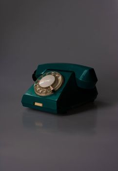 Retro swivel green phone on dark background.