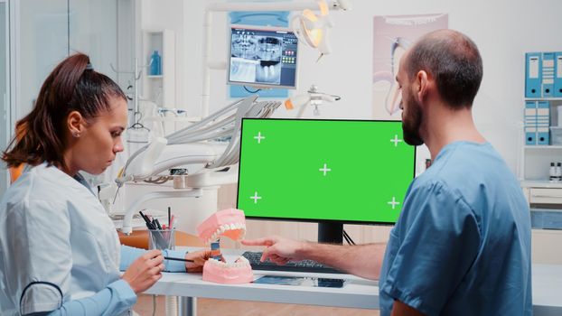 Dentist and nurse looking at green screen on monitor and analyzing teeth layout for stomatological care. Man and woman working with dental equipment for dentistry and teethcare.
