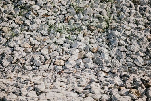 strengthening the slope with stones behind the wire. grey texture. construction. Granite stones behind a metal grate