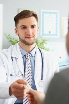 Portrait of male doctor in uniform give tablets in blister to patient. Specialist advice medication for treatment. Medicine, pharmacy, cure, help concept