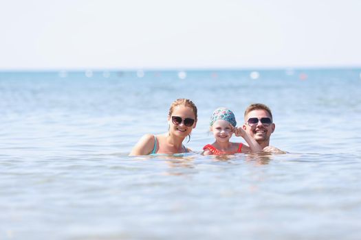 Portrait of happy family posing for picture together in sea or ocean. Memorable vacation together, family holiday, quality time. Summer, trip, joy concept