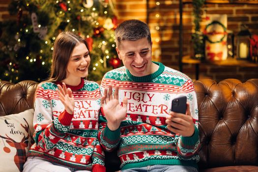 Family congratulates friends Merry Christmas on video communication. Couple sharing good news with friends and family on video chat during self isolation. Virtual celebration with friends video call.