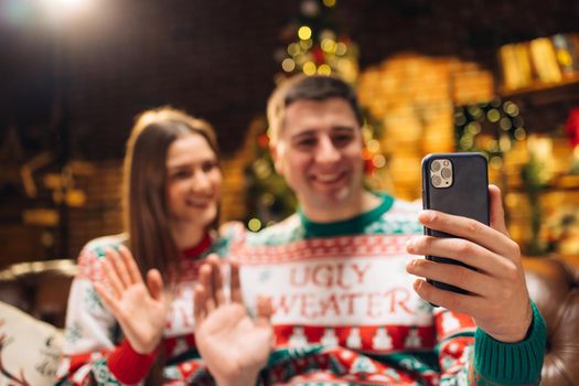 Young couple using smart phone talking to family congratulates Merry Christmas by video call conference app. Modern technology easy and comfort usage, New 2022 Year congrats remotely concept