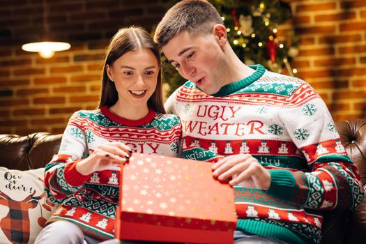 Christmas gift woman opening present with surprise sexy underwear laughing enjoying funny joke with boyfriend celebrating festive holiday at home.