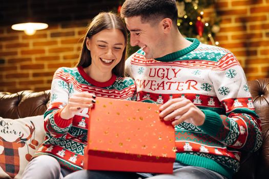 The woman is surprised and excited after opening received gift box. Concept of holidays, romance, surprise, e-commerce, Xmas, Holiday miracle. Happy man is making christmas gift to his beloved woman.