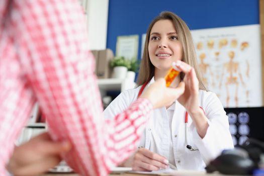 Portrait of qualified female doctor give medications in bottle to patient for faster recovery. Woman on appointment get advice from nurse. Medicine concept