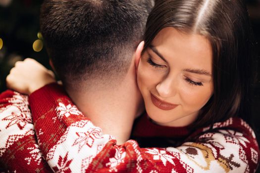 Close up of young beautiful woman hugging man holding Christmas present. Family tradition. Exchange of gifts. Christmas holidays celebration concept