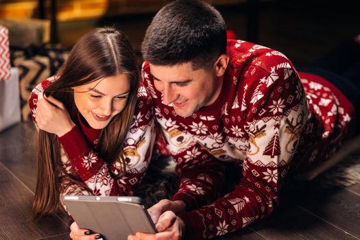 Nice couple in love with beautiful decorated living room. People using tablet. Celebration atmosphere. Online Shopping. Happy Smiling Young couple with Wireless Tablet buying online. e-shopping.