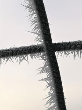hoarfrost on two crossed black thin iron bars as a close up