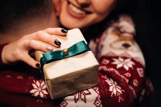 Close up of young beautiful woman hugging man holding Christmas present. Family tradition. Exchange of gifts. Christmas holidays celebration concept