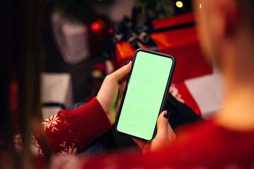 Couple using smartphone for christmas video call with green mock up screen. Christmas, festivity and communication technology.
