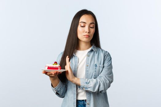 Social distancing lifestyle, covid-19 pandemic, celebrating holidays during coronavirus concept. Reluctant arrogant asian girl taking care of body, rejecting dessert, unwilling eat birthday cake.
