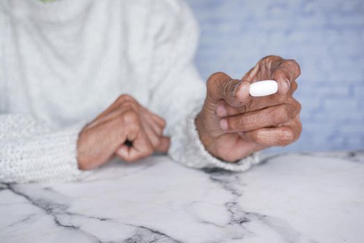 senior women holding a medical pills while sited .