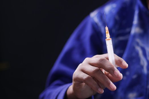 drug addiction concept with hand holding pills and syringe laying on floor .
