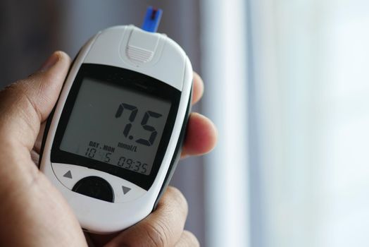 young man's hand measure glucose level at home.