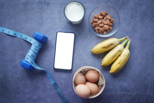 smart phone with empty screen , eggs , milk and almond nut in table .