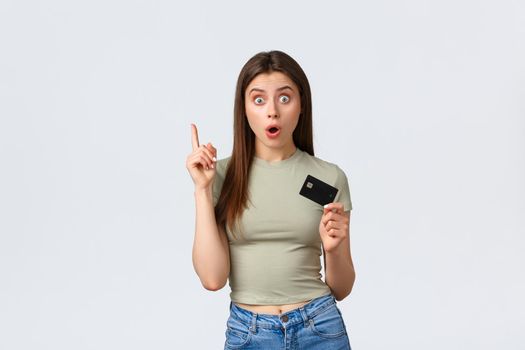 Shopping mall, lifestyle and fashion concept. Woman have great idea what buy for gift, raising index finger in eureka gesture, have suggestion, holding credit card over white background.
