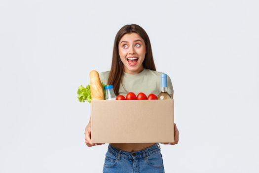 Online home delivery, internet orders and grocery shopping concept. Excited woman satisfied with quality of deliver service from local shop, holding groceries in box and smiling amazed.