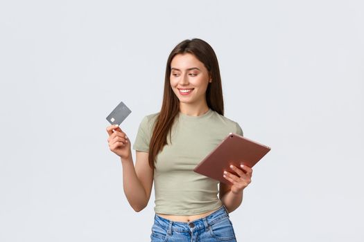 Fashion and beauty, lifestyle and shopping concept. Smiling good-looking female customer, girl making online order with credit card and digital tablet, shop in internet, white background.