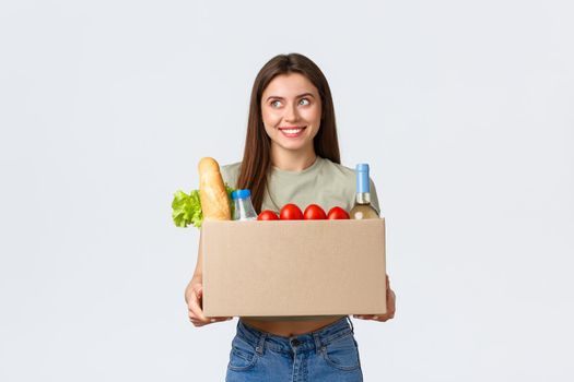 Online home delivery, internet orders and grocery shopping concept. Excited woman satisfied with quality of deliver service from local shop, holding groceries in box and smiling amazed.