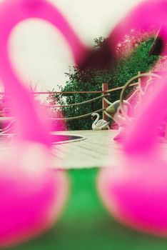 Two little flamingos kiss on the green grass in front of the pool. Flamingos in the form of a heart. Coasters for the pool. The concept of summer pastime. Beach summer composition