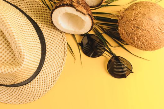 Summer composition. Tropical palm leaves, hat, glasses and broken coconut on a sandy background. The concept of the summer season, parties and heat. Flat lay, top view, copy space